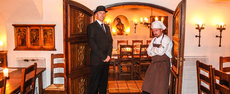 Murder mystery with butler and chef posing in front of the dining hall